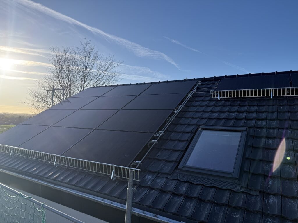 Dach mit Solarmodulen und Dachfenster, umweltfreundliche Energiegewinnung durch Solarenergie auf einem modernen Hausdach.
